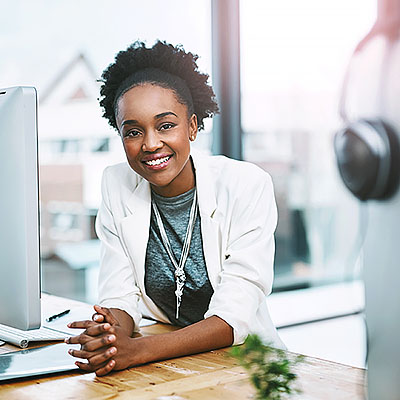 Employee, portrait and black woman with a smile, office and computer with development, career and professional. Face, female person and consultant with startup success, technology and confidence