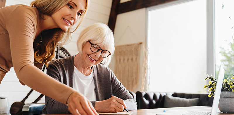 Insurance agent standing in front of laptop and giving advise to senior woman.